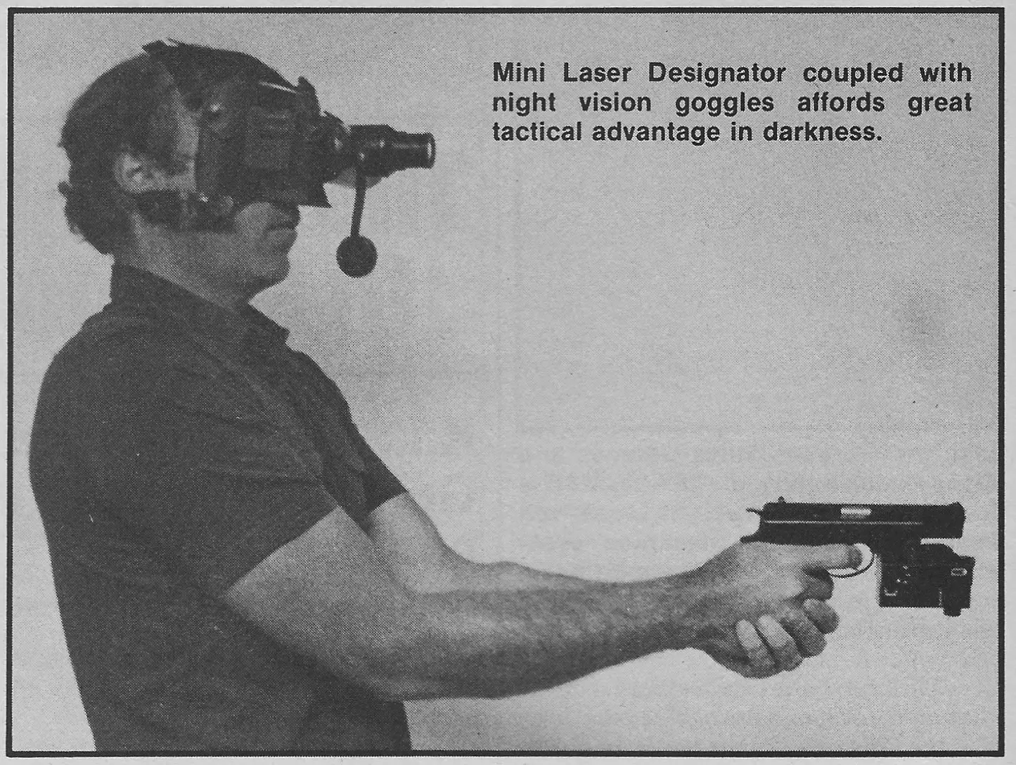 A man wearing night vision goggles is holding a Mini Laser Designator attached to a pistol, demonstrating its tactical advantage in low-light conditions.