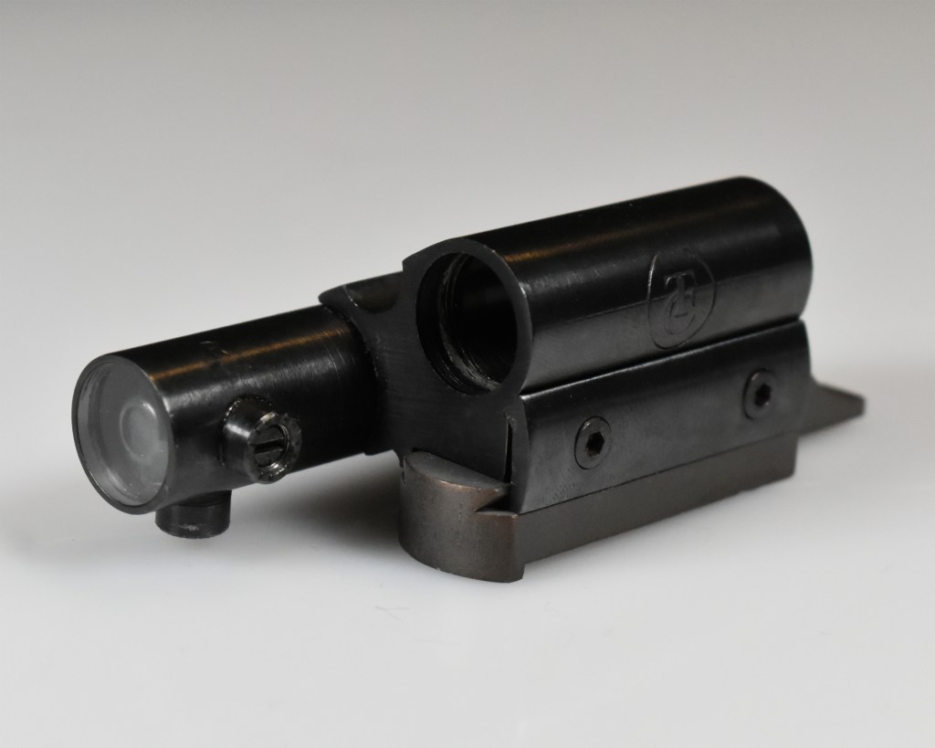 A close-up image of the TC Insta-Sight collimator sight, highlighting its sleek design with a small lens on one end, a mounting base, and a black finish.