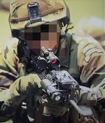 Soldier aiming a rifle mounted with a tactical light and scope, wearing camouflage uniform and helmet.