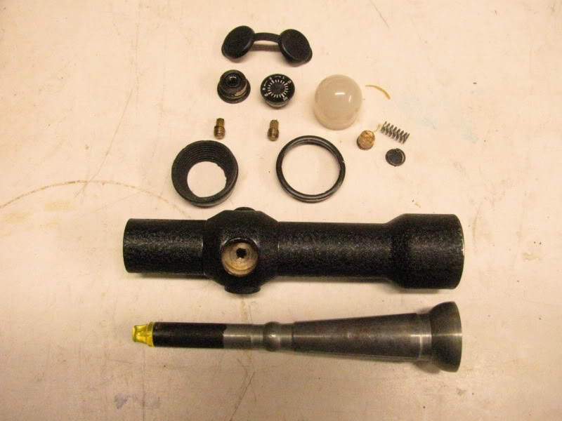 Disassembled parts of a rifle scope, including the main body, lenses, and miscellaneous components arranged on a flat surface.