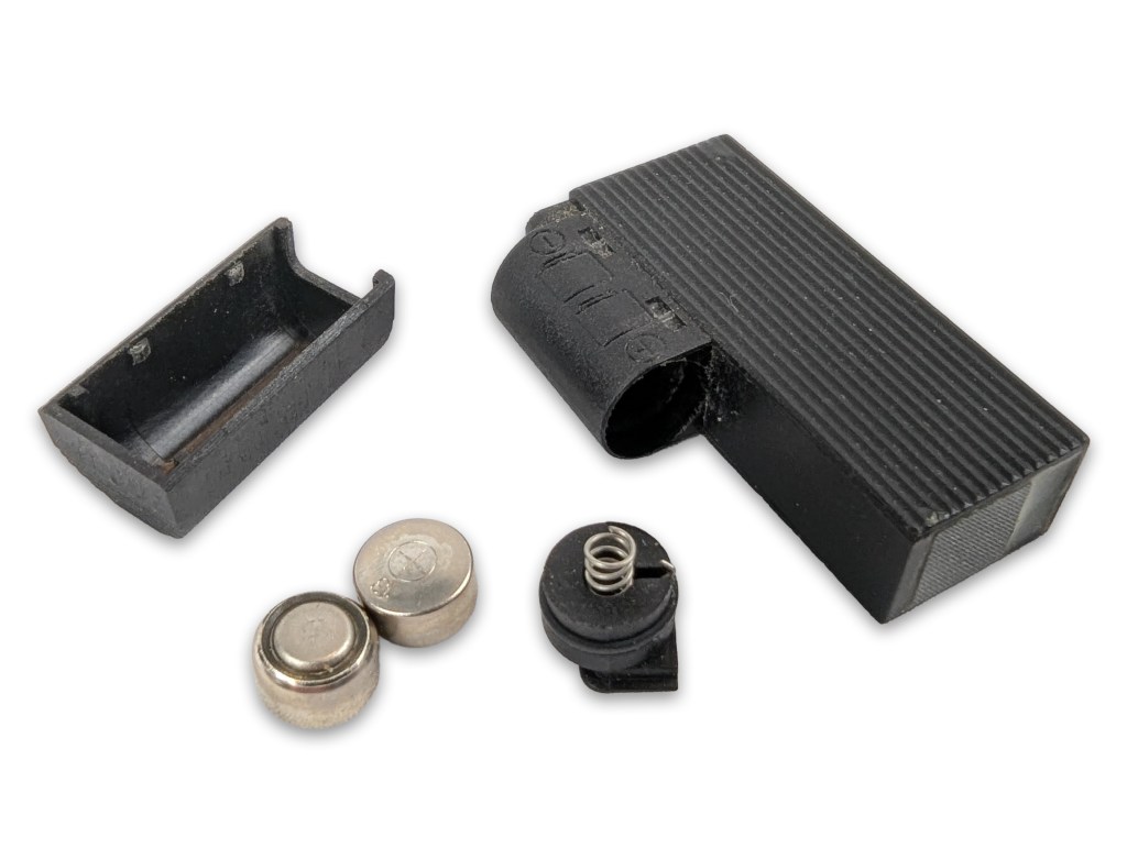 Detachable housing and components of the Subminiature Electronic Dot Sight, including batteries and a spring mechanism.