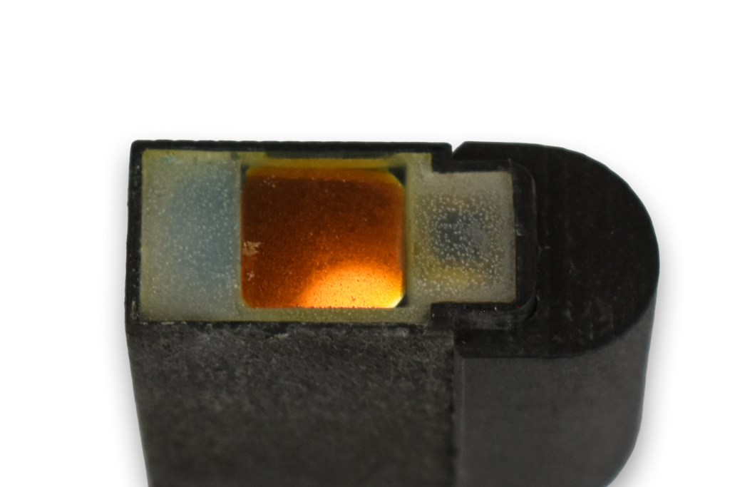 Close-up view of a sub-miniature red dot sight showing its lens and internal components.