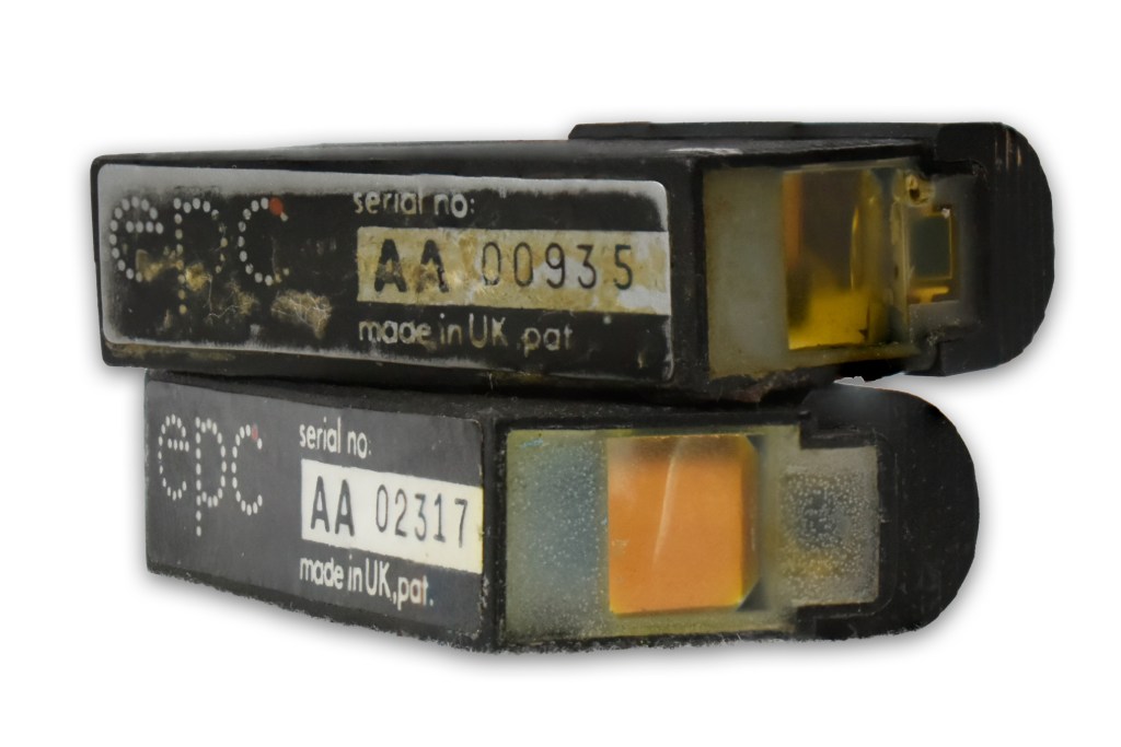 Close-up of two subminiature sights with visible serial numbers and wear, showcasing their design and construction.