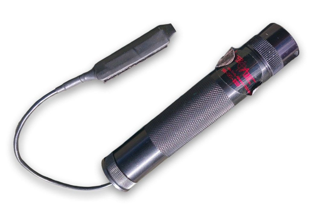A compact flashlight with a textured grip, remote pressure switch, and a halogen-beam bulb, designed for tactical use.