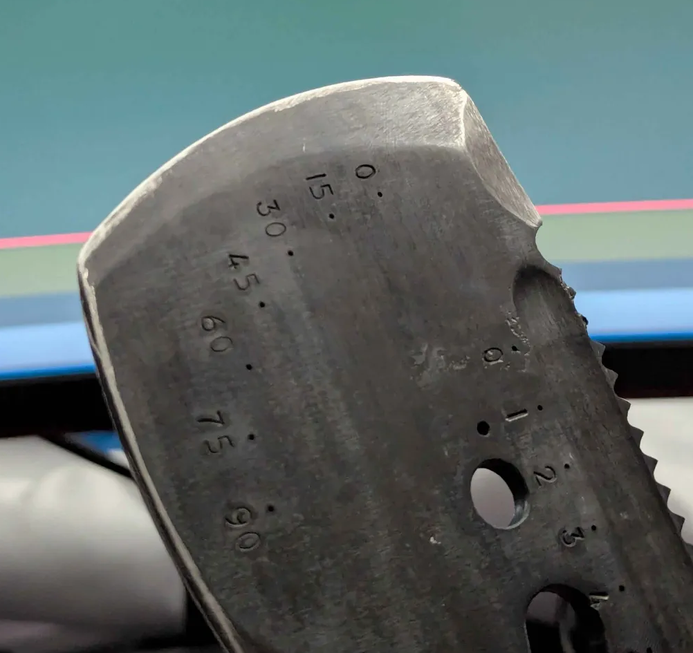 Close-up of a metal tool with measurement markings, showing angles from 0 to 90 degrees.